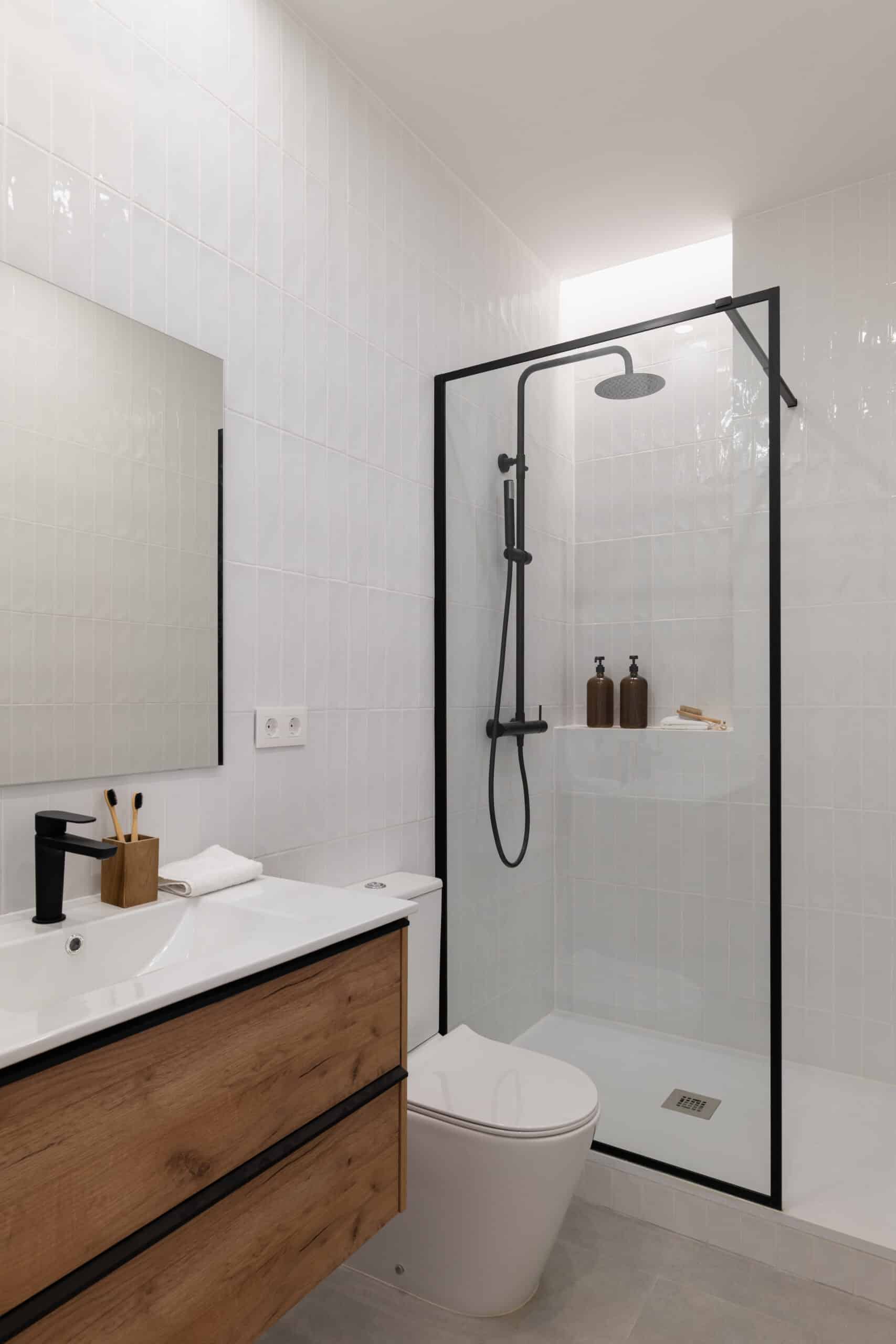 Salle de Bain Moderne Bois Noir et Blanc Design Salle de bain moderne avec carrelage blanc vertical, meuble-lavabo bois, robinetterie noire et douche à l'italienne. Prises murales visibles.